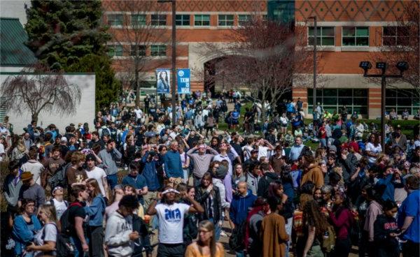 A large group of people, some of them wearing special glasses for a solar eclipse, gather on the Allendale Campus.